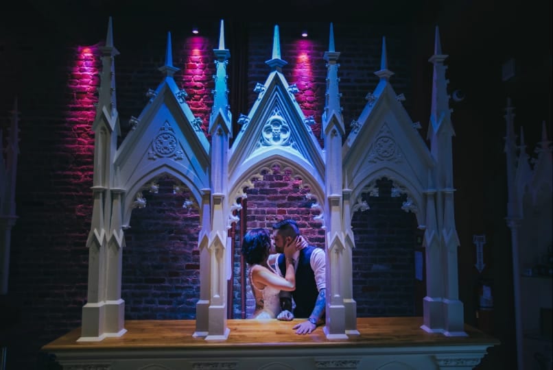 Wedding couple embracing under a Gothic-style arch backdrop at White Eagle Hall